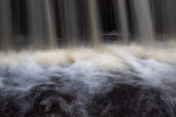 a long exposure view of a small fast river, beautiful water formations, autumn landscape, november in nature