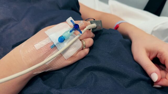 Close-up of an intravenous drip in the hand of a patient lies on bed in the hospital. High quality 4k footage