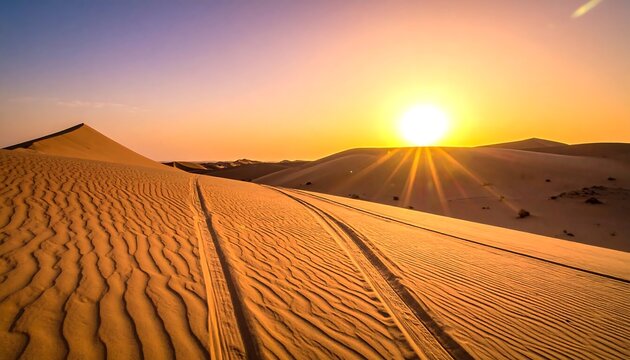 Desert landscape under a vibrant sunset sky with tire tracks crossing dunes