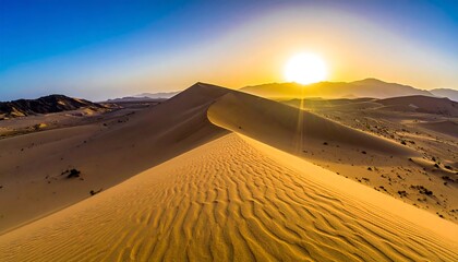 Desert landscape with golden dunes under a sunny sky with mountain range silhouette on the horizon