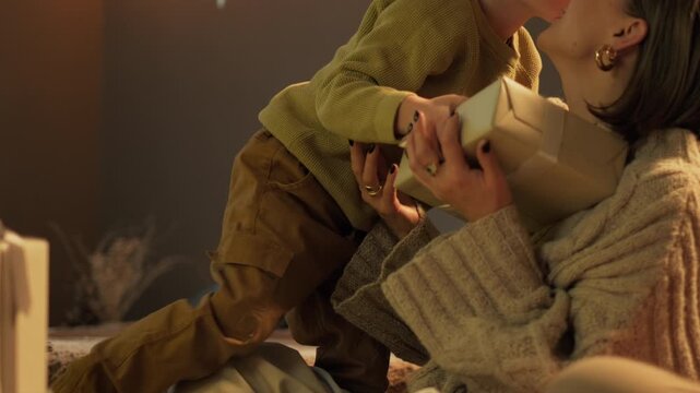 Little cute boy giving Christmas gift to his mother, loving son embracing excited mother. Winter holidays care and surprise