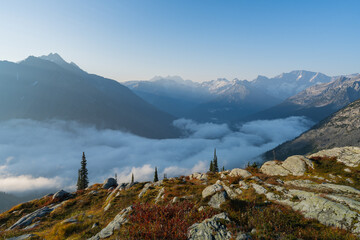 Majestic mountains pierce the sky above a sea of ethereal clouds. Serene view.