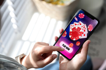 Woman playing online poker on mobile phone indoors, closeup © New Africa