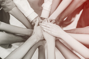 People stacking hands together indoors, closeup. Color toning