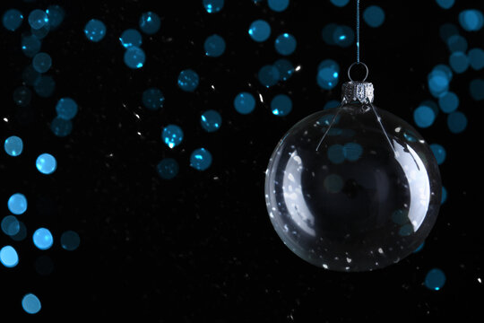 Christmas ball against blurred lights on black background