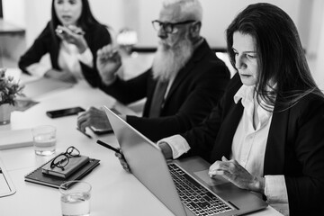 Business team doing financial market data analysis inside hedge fund office - Bitcoin, investing money and cryptocurrency concept - Main focus on woman face - Black and white editing