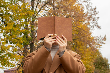 Woman covering her face with a notebook