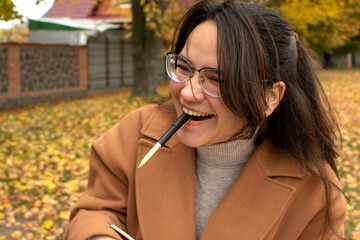 Young attractive smiling woman holding pen in mouth