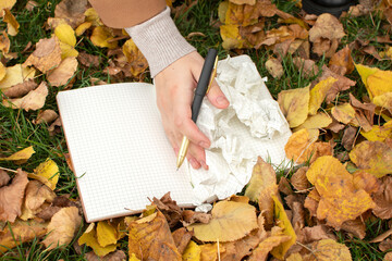 A woman's hand sweeps away torn pages from a notebook