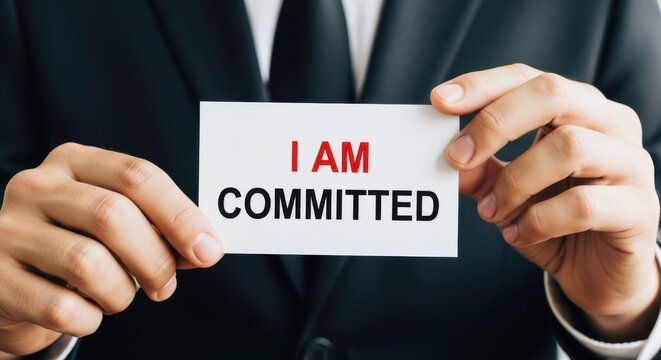 Businessman displays a card stating i am committed in a professional setting