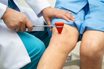 Asian doctor knock on knee reflex nerve for check and treatment senior patient in hospital.
