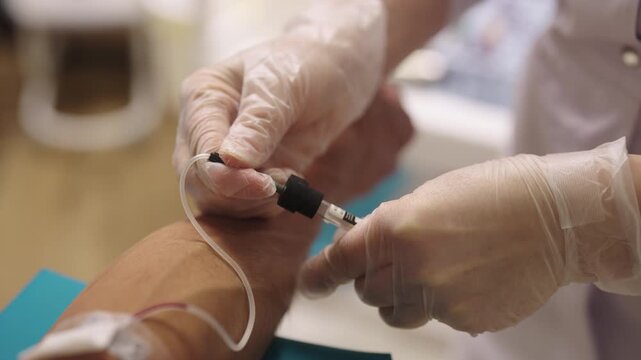 Healthcare worker wearing medical gloves collecting blood sample from patient vein for diagnostic testing, health check-up, and laboratory analysis, close-up. Shooting in slow motion.