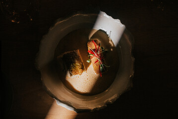 A bowl of food with a white rim and a red garnish. The food is in the center of the bowl and is surrounded by a shadow