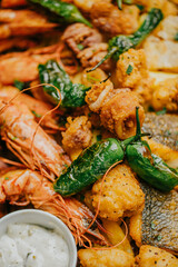 A plate of food with shrimp, fish, and vegetables. The shrimp is on the left side of the plate, and the fish is on the right. The vegetables are scattered throughout the plate