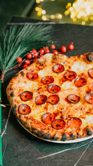 A pizza with pepperoni on it is sitting on a plate. The pizza is surrounded by pine needles, which give the scene a festive and cozy atmosphere