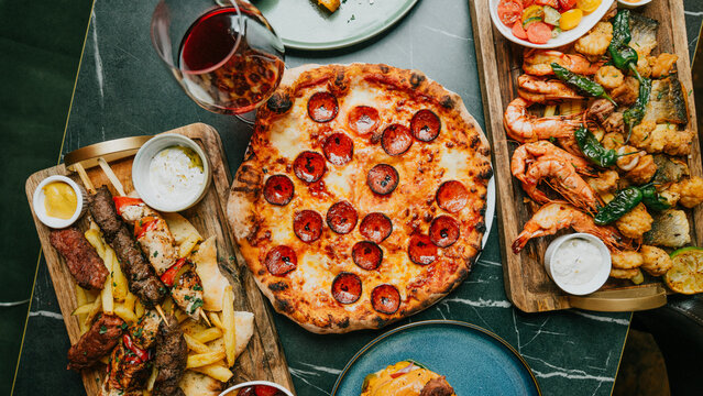 A table with a variety of food and drinks, including pizza, shrimp, and a bottle of wine