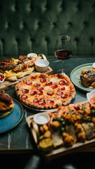 A table with a variety of food and drinks, including pizza, chicken wings, and a bottle of wine