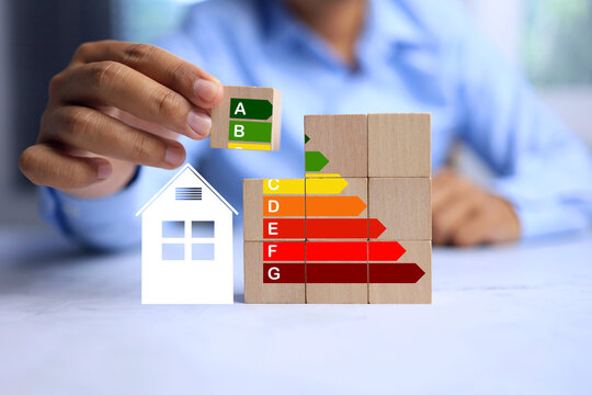 energy efficiency rating labelling concept with a man arrange wooden cube to rating indication for economy class of electric household appliances
