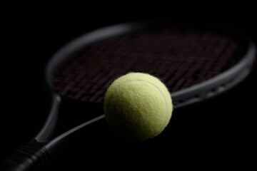 Tennis racket and ball on black background
