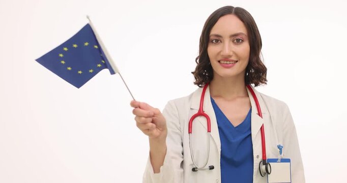A passionate health advocate in a white coat proudly waves the European Union flag. Her smile radiates hope and commitment to health across Europe, inspiring unity and care.