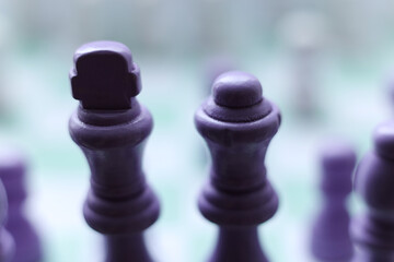Macro photograph of a purple chess king and queen illuminated by soft backlight on a pastel chessboard. Minimalistic atmospheric composition symbolizing power, unity, strategy, leadership