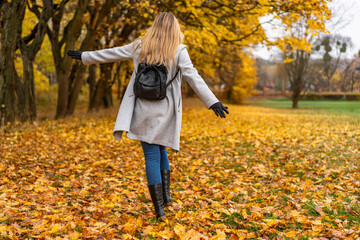 Beautiful middle-aged woman enjoying walk in autumn scenery. Back view	
