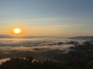 Sunrise over a misty valley with rolling hills and trees