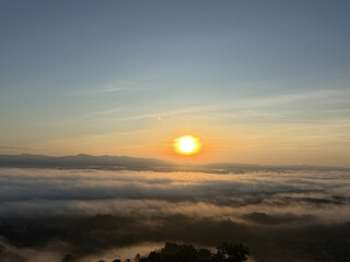 Fototapeta premium Sunrise over a sea of clouds with distant mountains