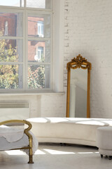 Vintage interior with gold-framed mirror and sunlight pouring through large loft windows