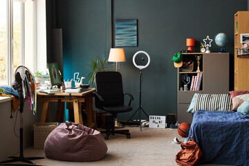 Modern teenager bedroom featuring organized workspace with computer, ring light, bookshelves, bed,...
