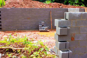 Workers are building masonry block wall on construction site. foundation work in progress.