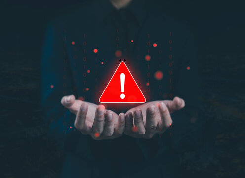 Hands presenting a glowing warning symbol with digital code particles, representing cybersecurity threats, system alerts, risk management, data protection, and critical caution in modern technology.