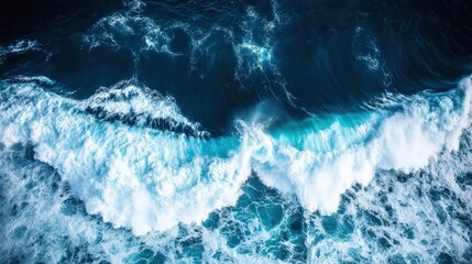 Aerial view of ocean waves crashing against the shore, showcasing vibrant blue water and foamy white crests.