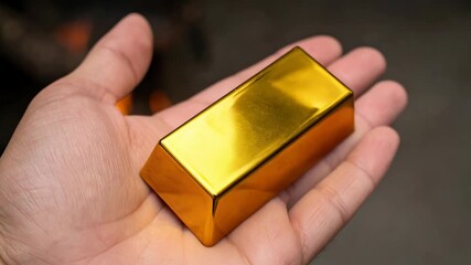 Hand holding valuable gold bar represents solid investment for wealth amid labor market shortages, secure asset against volatile global economy and financial uncertainty