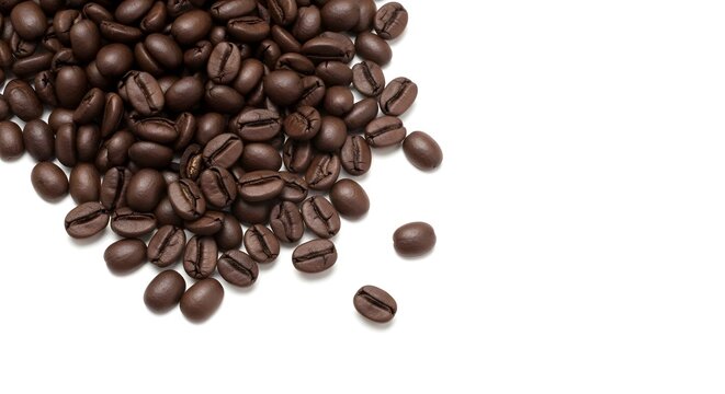 Roasted coffee beans scattered on a pure white background, ready for brewing a fresh, aromatic and delicious beverage.