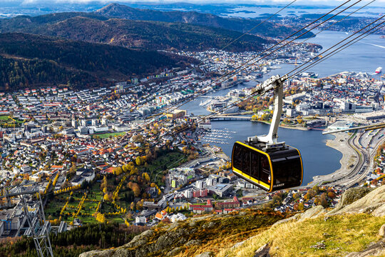 Bergen, Norway - 19 October 2024: Yellow Ulriken cable car descending over autumn Bergen, Norway. Stunning panoramic view of colorful fall trees, city rooftops, iconic Scandinavian travel scene.