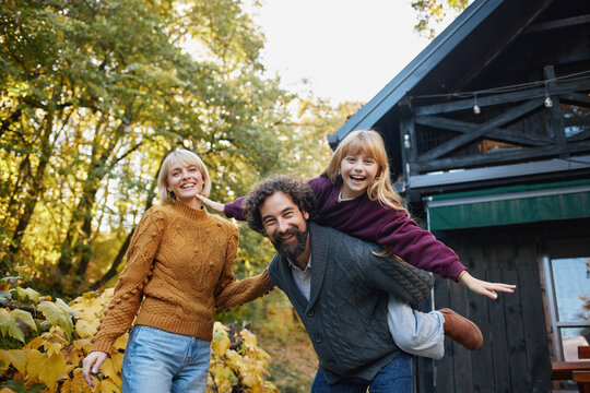 A family poses happily in vibrant autumn foliage during a weekend outing. The warm atmosphere captures their smiles and playful spirit while surrounded by nature. - Powered by Adobe