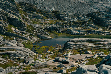 A small lake surrounded by rugged rocks and sparse vegetation in the hills.