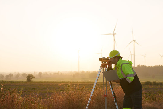 Civil engineers are using a camera to measure the distance of roads in a wind turbine farm.