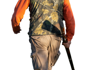 Mature hunter man holding a shotgun and walking through a field
