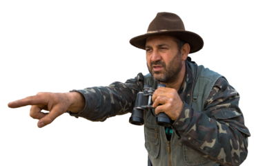 A hunter with a gun in his hands in hunting clothes in the autumn forest in search of a trophy. A man stands with weapons and hunting dogs tracking down the game.