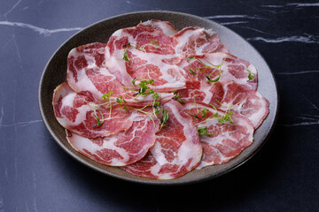 Plate of Marbled Raw Meat Slices Garnished with Fresh Herbs
