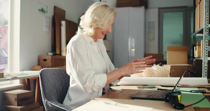 Fist pump, ecommerce and laptop with woman in warehouse for delivery confirmation, success and bonus. Shipping good news, online order and courier distribution with mature person as entrepreneur