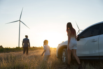 Family happiness and bonding at sunset, relaxation and renewable energy with innovation, wind turbines and sustainable energy, travel, relaxation and the environment.  © YaMo
