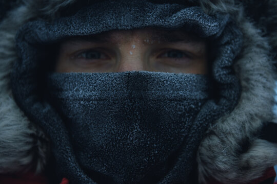 Close-up portrait of a man wearing a warm fleece balaclava under a fur hooded coat with only his eyes visible