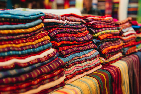 Close-up of a stack of assorted patterned scarves folded on a table for sale in a shop, Morocco