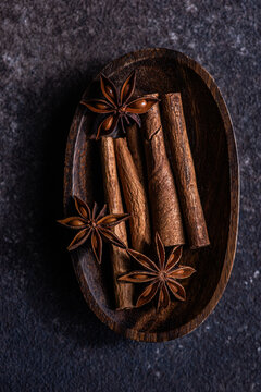 Close-up overhead view of cinnamon sticks and star anise in a wooden bowl on a table