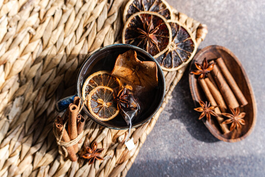 Overhead view of a cup of Mulled tea with assorted spices on a rustic table mat