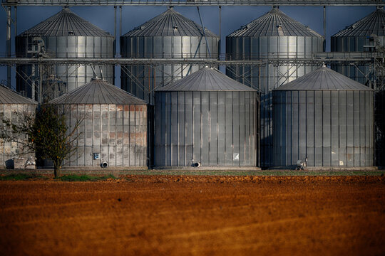 Close-up of metal Silos on a farm next to a ploughed field, Piedmont, Italy