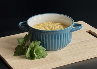 Mac and cheese in a blue bowl, standing on a wooden board